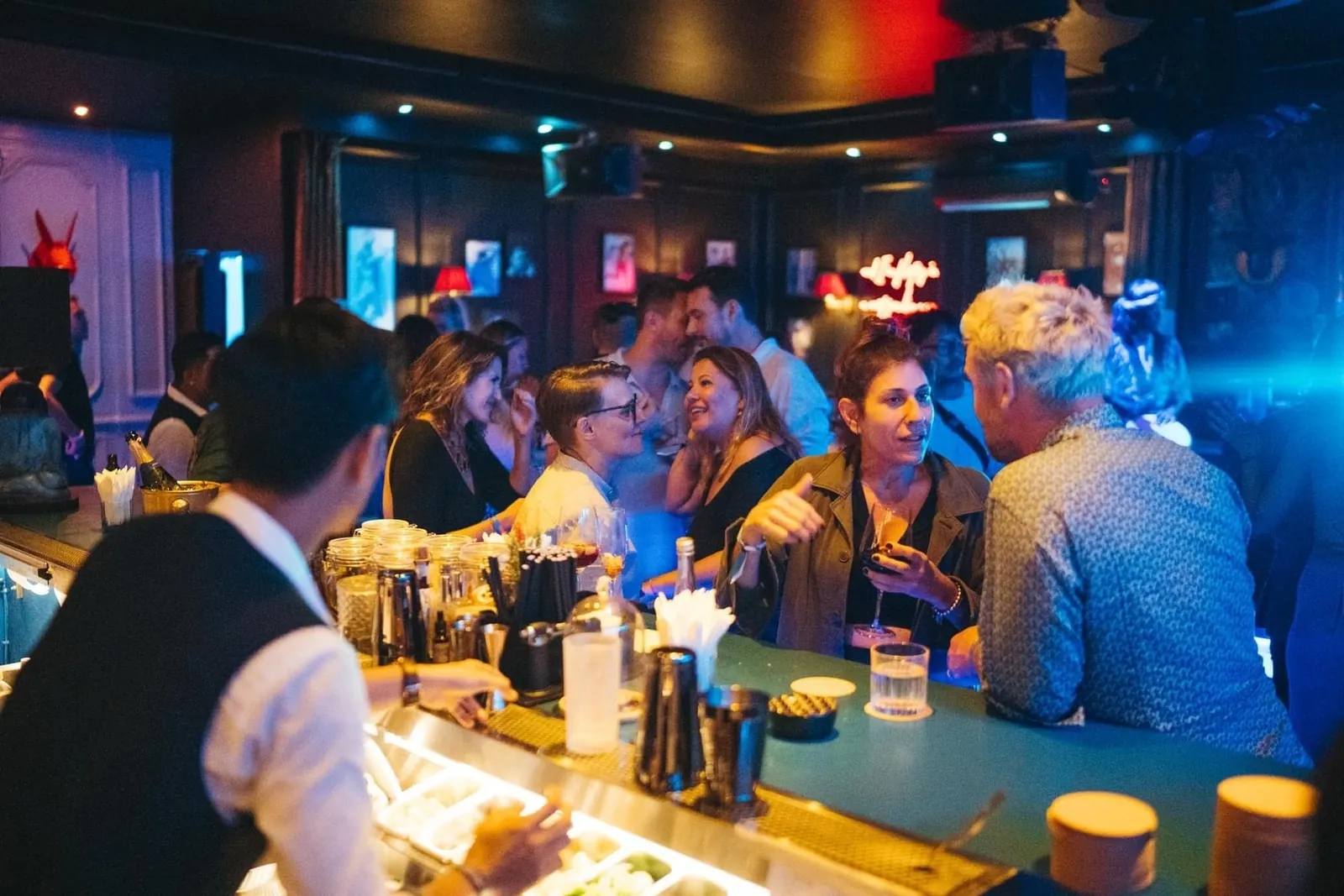 A crowd at the bar at The Blue Door in Ubud, with a bartender working in the foreground.